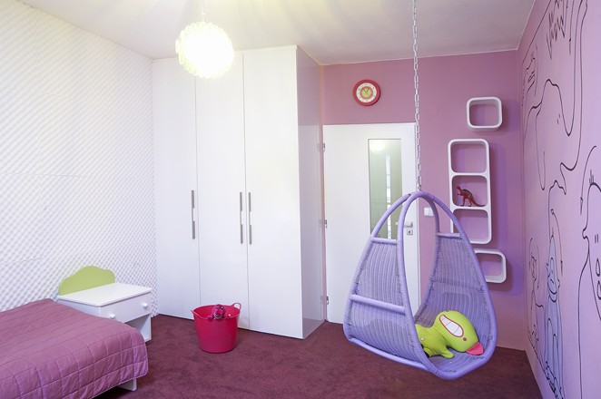 Specifickým prvkem pokoje je závěsná houpačka. Ukládání hraček řeší několik závěsných polic a plastové koše 
