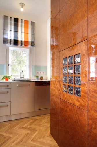 Dřevěný obklad stěny v kuchyni je nový, ale zamýšlený jako odkaz na dobu vzniku domu. Vyroben byl z ořechové kořenové dýhy, charakteristické pro nábytek první republiky