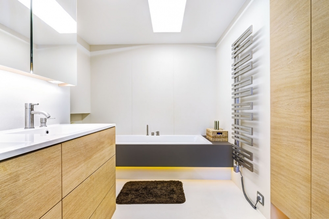 Také koupelny prošly kompletní rekonstrukcí a prostor v nich je lépe využitý. Vizuálně navazují na podobu celého bytu – převládají velké světlé plochy doplněné o dubové dřevo a neutrální odstíny šedé a hnědé