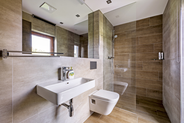 Také v menší koupelně, do které se vstupuje přímo z pokoje pro hosty, zvolili majitelé prostorově úsporné řešení sprchového koutu typu walk-in. K odkládání předmětů slouží spodní okraj mělké niky se zrcadlem