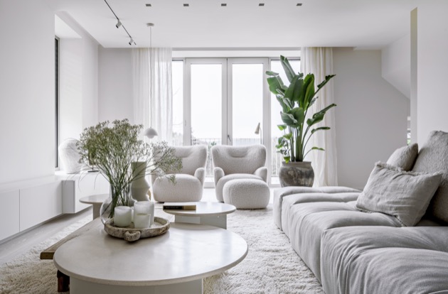 Nejen užitím lomených odstínů bílé barvy dnes obývací prostor dýchá klidem. Vlídnost prostředí podporují také dvě pohodlná křesla (Gervasoni) na vlněném koberci (Carpet Design), doprovázená závěsným lustrem Flowerpot VP1 v designu Vernera Pantona (&amp;Tradition). 