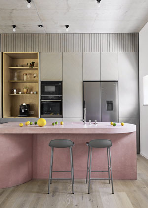 Hlavnímu obytnému prostoru dominuje velký růžový ostrůvek z betonu: „Růžovou barvu jsme zvolili pro její hravost a také nám příjemně kontrastovala s industriálním charakterem stropu, který jsme chtěli trochu potlačit. Součástí ostrůvku jsou jak úložné prostory, tak kuchyňské spotřebiče,“ vysvětlují koncept jeho autoři ze studia ti architekti.