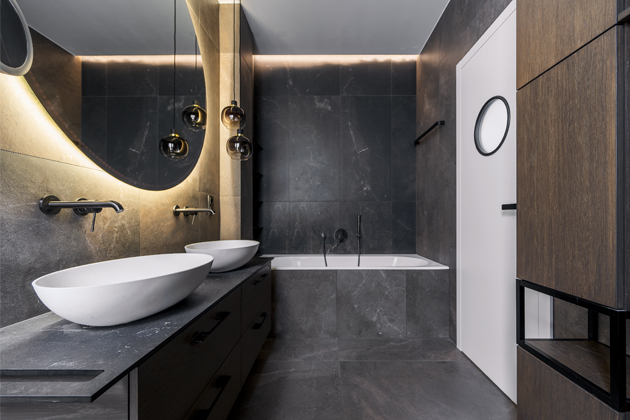 Efektn&iacute; obklady a&nbsp;dlažby Regina  v koupeln&aacute;ch (Archceram) dodal  Archtiles. Sanit&aacute;rn&iacute; keramiku doprov&aacute;zej&iacute; baterie (Grohe)  z&nbsp;brou&scaron;en&eacute;ho čern&eacute;ho chromu. Deska pod umyvadly v&nbsp;hlavn&iacute; koupelně je  vyrobena z&nbsp;kompaktn&iacute;ho lamin&aacute;tu (Arpa). O dod&aacute;vku sv&iacute;tidel do cel&eacute;ho domu se postarala firma Wirp.
